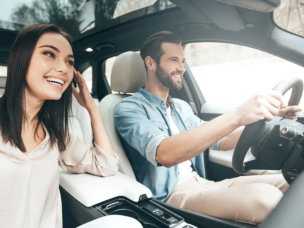 Happy couple driving after completing driving lessons at Success Driving School